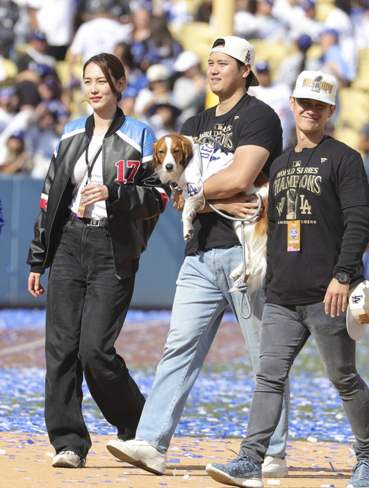 　ドジャースタジアムで行われた優勝報告会を終え、デコピンを抱いて引き揚げる大谷翔平。左は妻の真美子さん（提供・共同通信社）