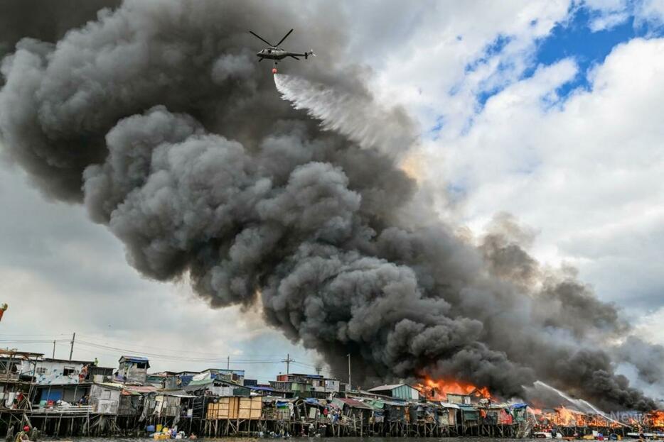 フィリピンの首都マニラのトンド地区で、消火作業に当たる空軍ヘリ（2024年11月24日撮影）。【翻訳編集】 AFPBB News