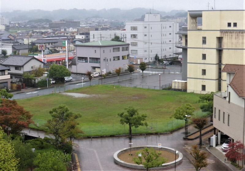 橿原市が売却する近鉄畝傍御陵前駅東側の市有地。中央の雑草が生えた更地と、その奥のフェンスで囲まれたアスファルト部分からなる。手前は駅前ロータリー＝同市大久保町で2024年10月29日午後2時20分、皆木成実撮影