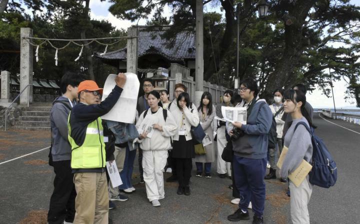 五色浜神社の前でボランティアガイド観光ボランティアガイドの説明を聞く生徒ら