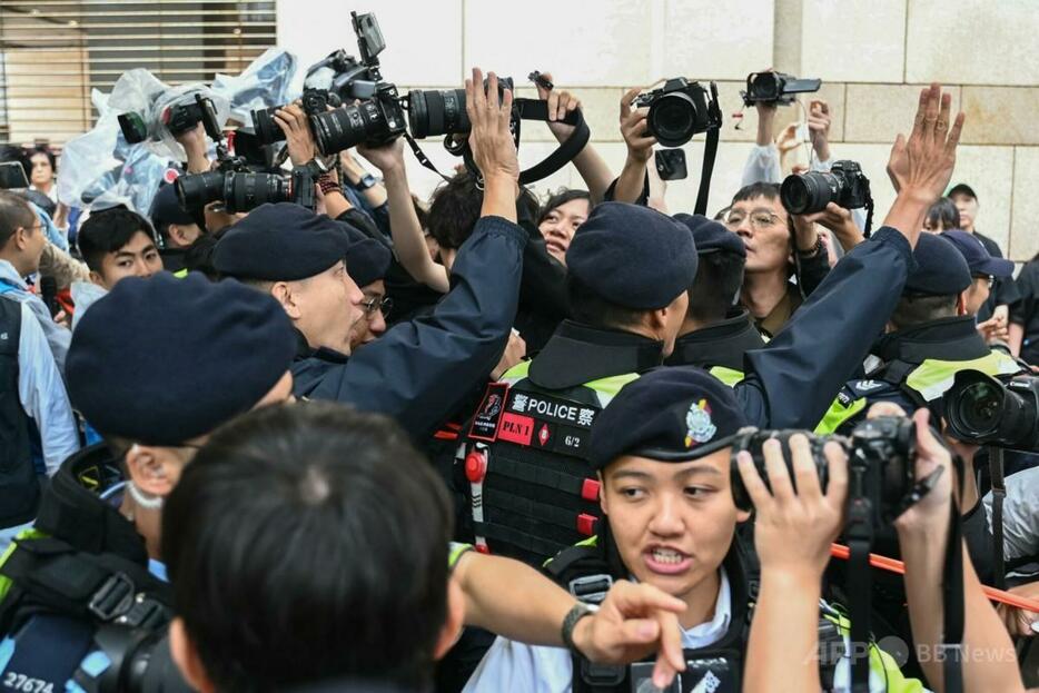 香港の西九龍治安判事裁判所前で、報道陣を制止する警察（2024年11月19日撮影）。【翻訳編集】 AFPBB News