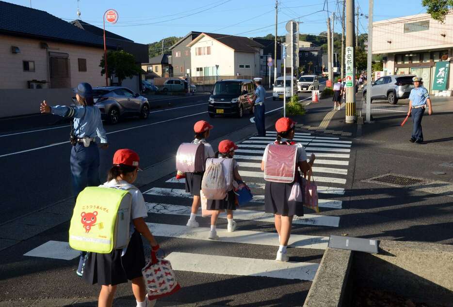 登校の安全を確保するため横断歩道に立つ警察官＝９月３０日朝、鹿児島市上福元町