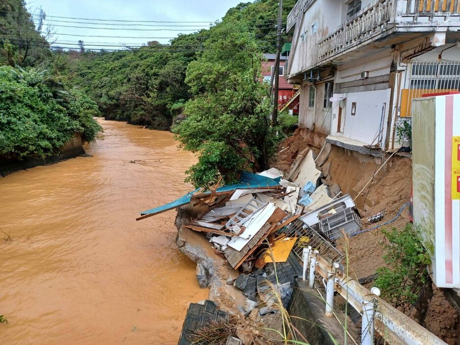 大雨の影響による崖崩れで、建物の一部が崩落した民宿＝9日午前10時16分、東村平良