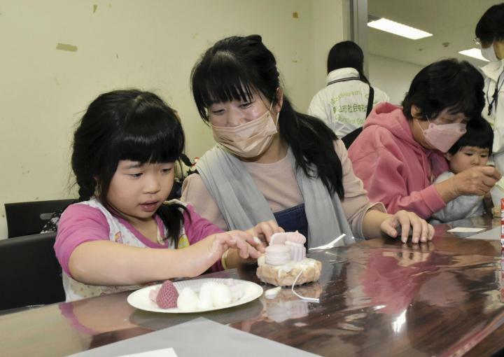 ろうでできた菓子を飾りアロマキャンドルを作る参加者