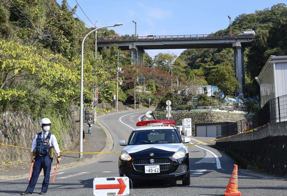 ダンプカーと乗用車が衝突した事故現場付近を警戒する警察官＝12日午後0時2分、広島市