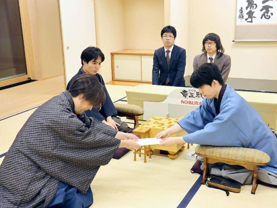 封じ手の封筒を渡す藤井聡太竜王（右）＝大阪府茨木市（日本将棋連盟提供）