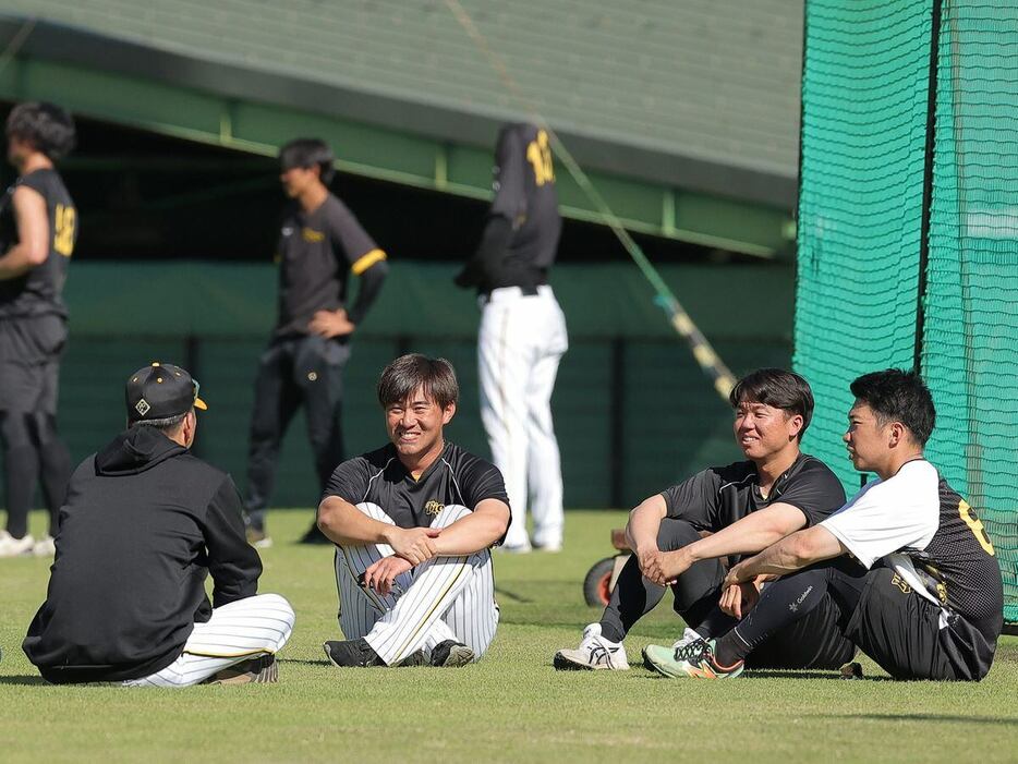 芝生に座り込み笑顔で話す（左から）藤川監督、桐敷、村上、石井。指揮官自らねぎらった＝安芸市営球場（撮影・根本成）