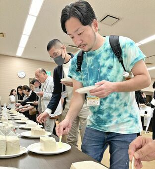 「島豆腐サミット」に出品された島豆腐１８点から試食する全国各地の豆腐屋関係者ら＝９日、那覇市の自治会館