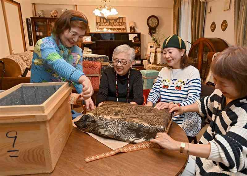 茶箱のふたに布地を合わせ、飾り箱のイメージを話し合う藤崎節子さん（左から2人目）ら＝1日、熊本市中央区