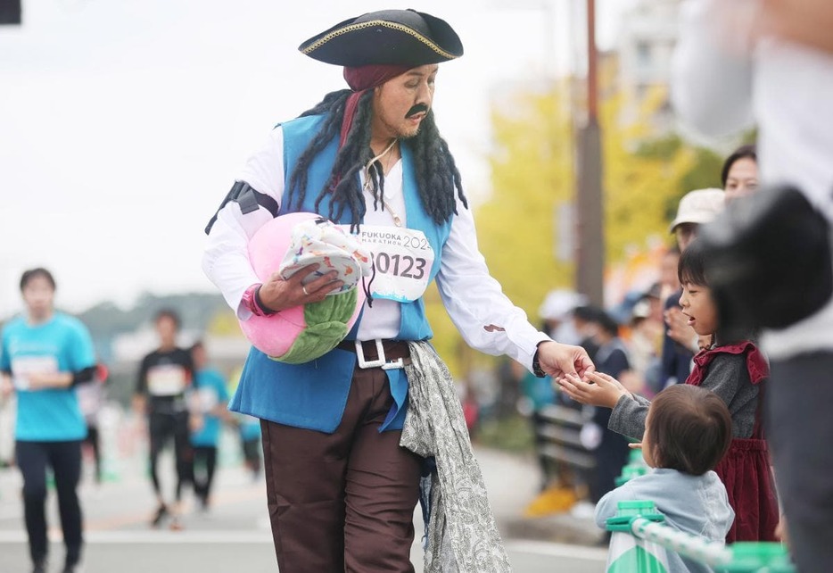 子どもにアメをあげながら進むランナー