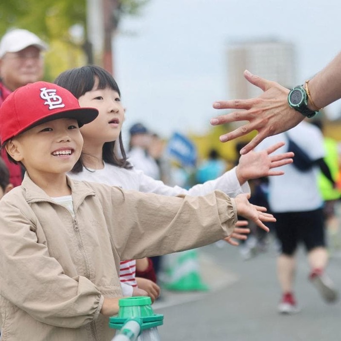 ランナーとハイタッチしながら沿道で応援する子ども