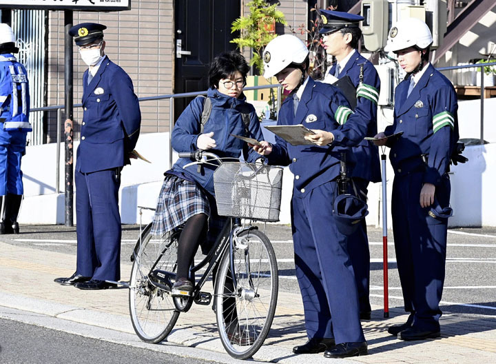 自転車利用者に罰則強化を周知する警察官＝福島市