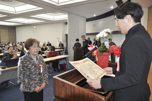 【選者の1人、佐佐木頼綱さんから表彰を受ける橋本さん＝鈴鹿市飯野寺家町の文化会館で】