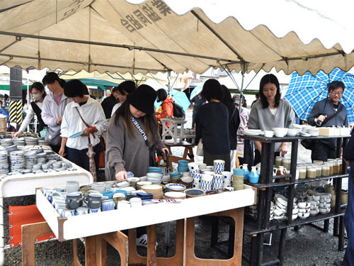 【買い物客でにぎわう器のつくり手市＝菰野町永井の三鈴陶器敷地内で】