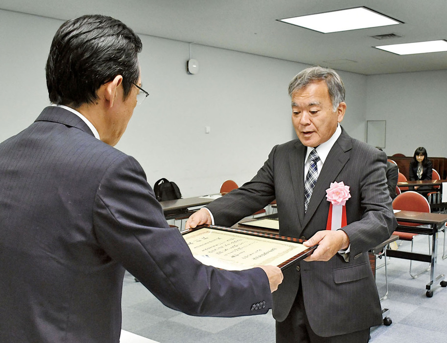 地頭所恵教育長から表彰状を受け取る与論島芭蕉布保存会の菊秀史会長（右）＝8日、鹿児島市の県庁