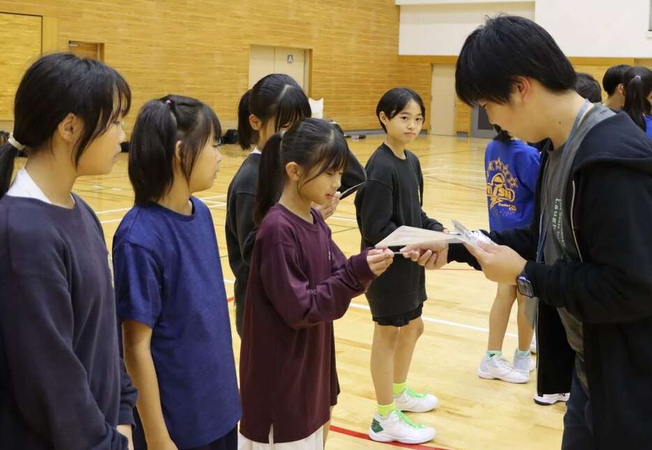 小学生のバスケットボールチームにガクチカクラブの活動をPRする大学生（右）（四天王寺大提供）