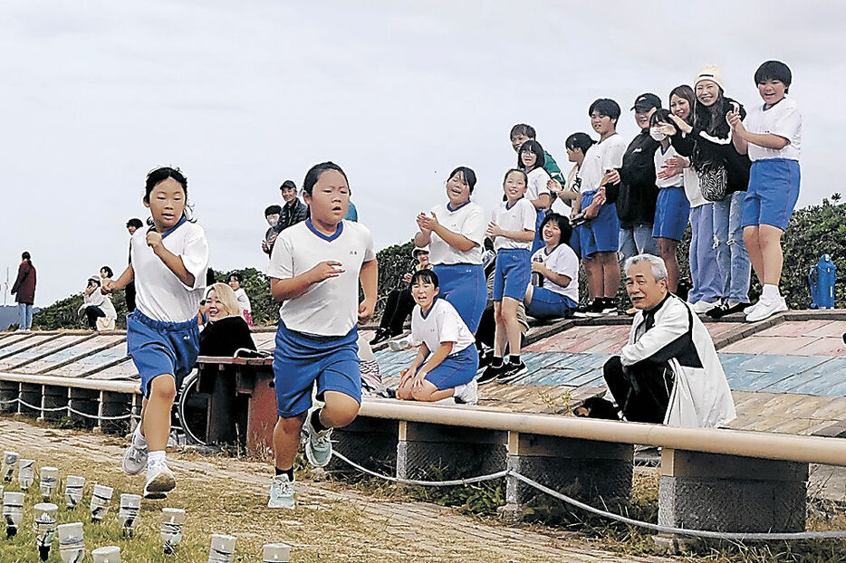 声援を受けながら走る児童＝志賀町富来領家町の「世界一長いベンチ」