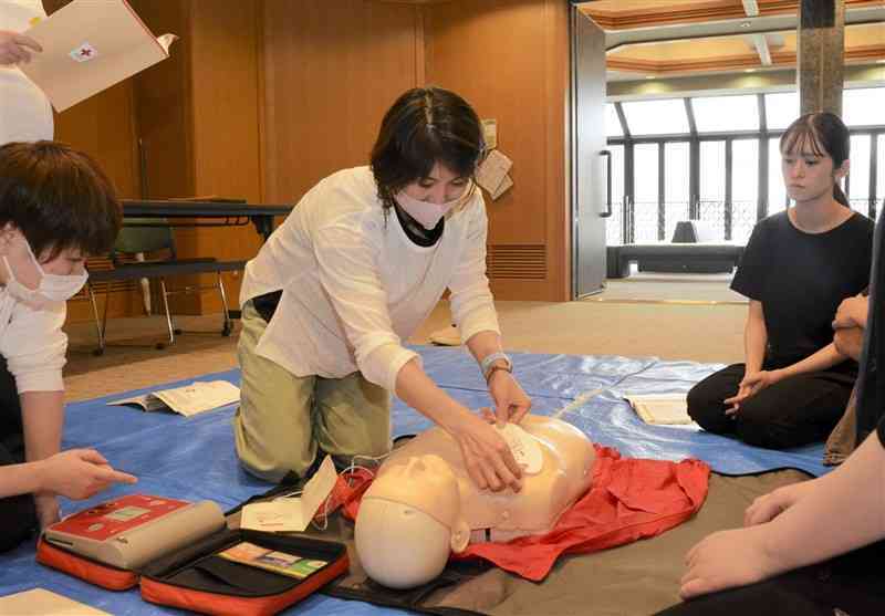 心肺蘇生などを学ぶ講習でAEDの使用法を学ぶ参加者＝3日、熊本市中央区