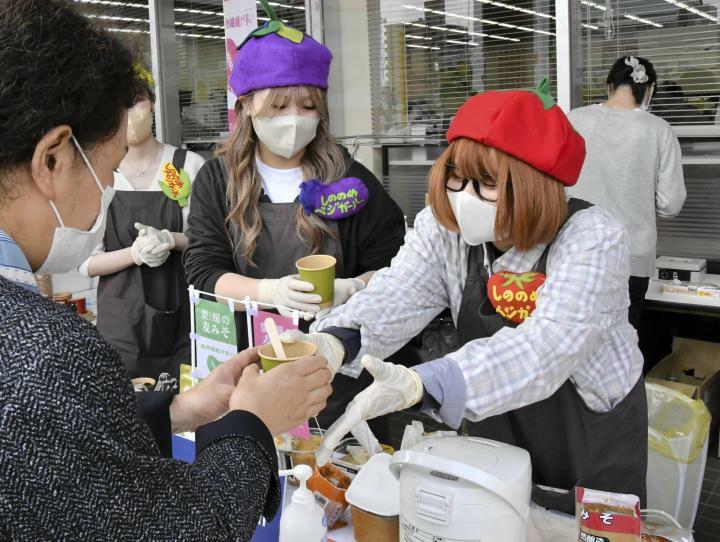 訪れた人に麦みそのみそ汁を手渡す松山東雲短大の学生（右）