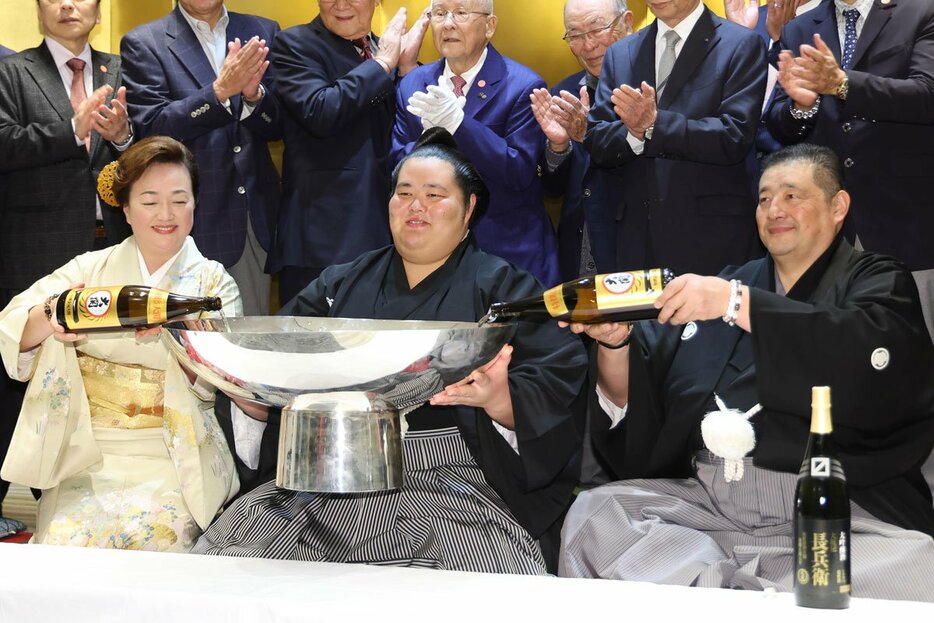 祝勝会で父の佐渡ケ嶽親方(右)、母・真千子さん(左)に大盃へ酒を注いでもらう琴桜