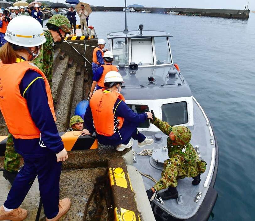 避難のため海上自衛隊の船に乗り込む住民役の学生ら＝１６日午前１０時３６分、鹿児島市桜島赤水町の赤水港