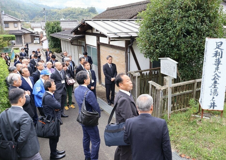 足利尊氏が生まれた際、産湯に使われたとされる井戸を見学する全国足利氏ゆかりの会の関係者ら＝京都府綾部市安国寺町で、庭田学撮影