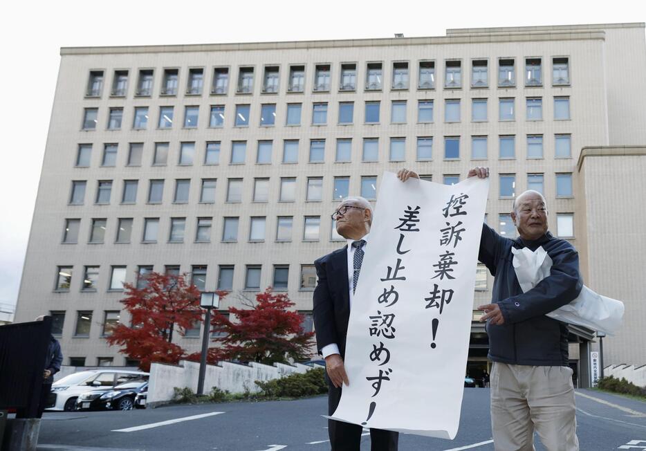 東北電力女川原発2号機の運転差し止めを求めた訴訟の控訴審判決を受け、仙台高裁前で紙を掲げる原告＝27日午後