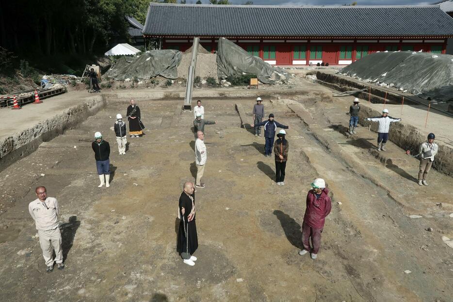 薬師寺の回廊西北角の発掘現場で、確認された礎石の据え付け穴などの上に立つ関係者ら＝7日午前、奈良市