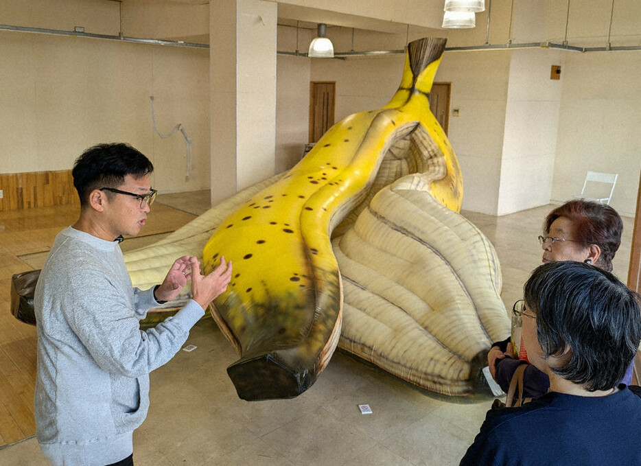 来場者にバナナの皮の作品について語る三塚新司さん（左）＝群馬県高崎市で２０２４年１１月１７日、増田勝彦撮影