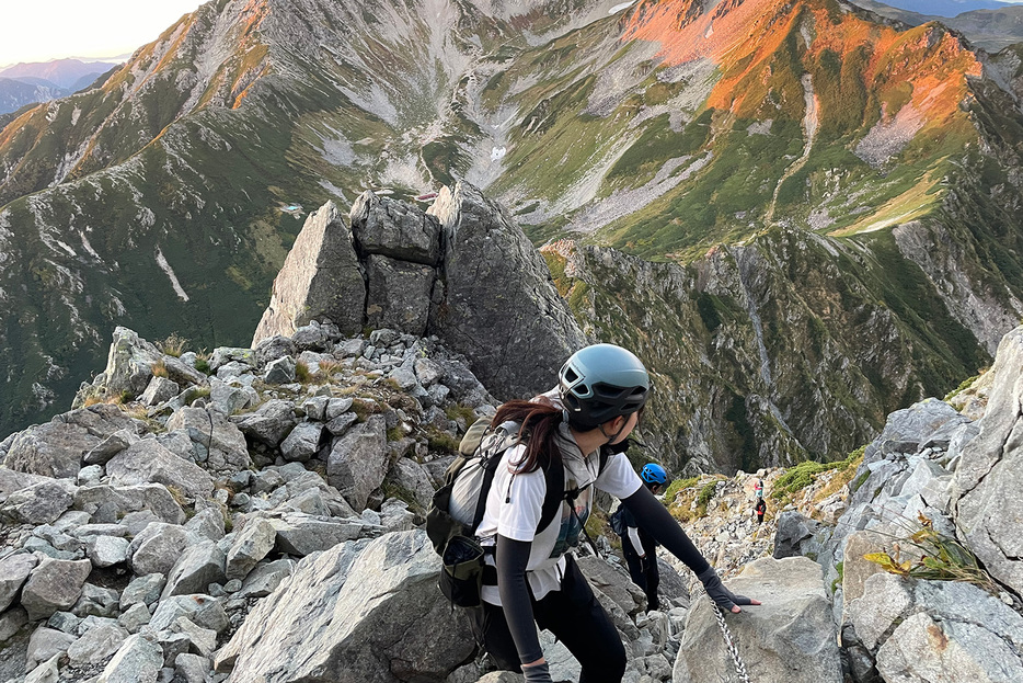 3点支持で岩場を慎重に登る女性登山者