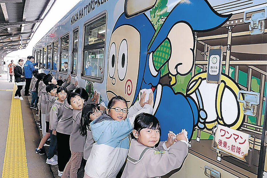 列車の車体をぞうきんで拭く園児＝ＪＲ氷見駅