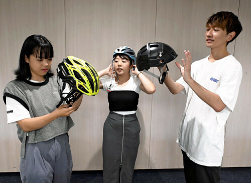 市販の自転車用ヘルメットを手に、アイデアを出し合う学生ら（８月、警視庁本部で）