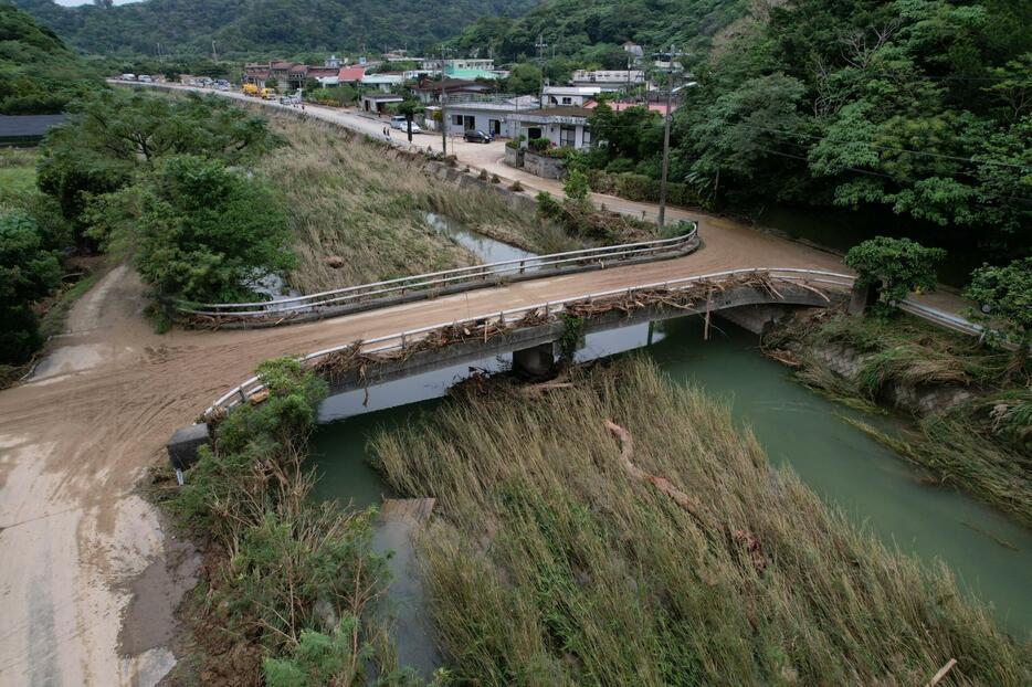 豪雨で氾濫した比地川。川には草が茂り、欄干には流木が残ったまま＝13日午後３時19分、国頭村比地（小型無人機で小川昌宏撮影）