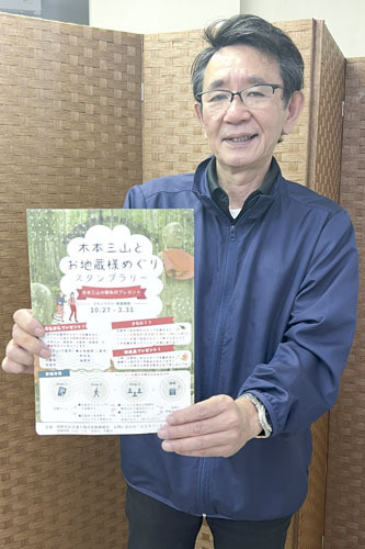 【スタンプラリー台紙を手に、参加を呼びかける伊東専務理事＝熊野市木本町のいこらい広場で】