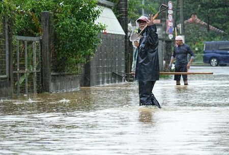 詰まった排水口の落ち葉などを片付ける人たち＝10日午前10時48分、名護市稲嶺（竹花徹朗撮影）