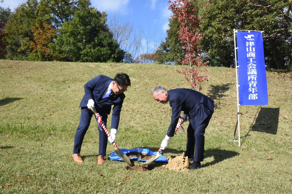 ハナモモの苗木を植樹する石川会長と谷口市長=岡山県津山市で