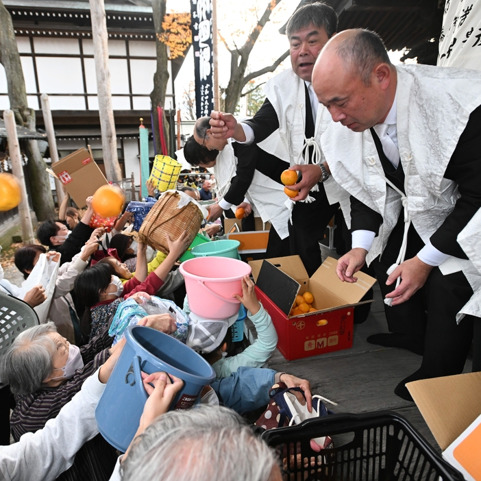 神社総代らが投げるミカンを、籠などで受け取ろうとする人たち