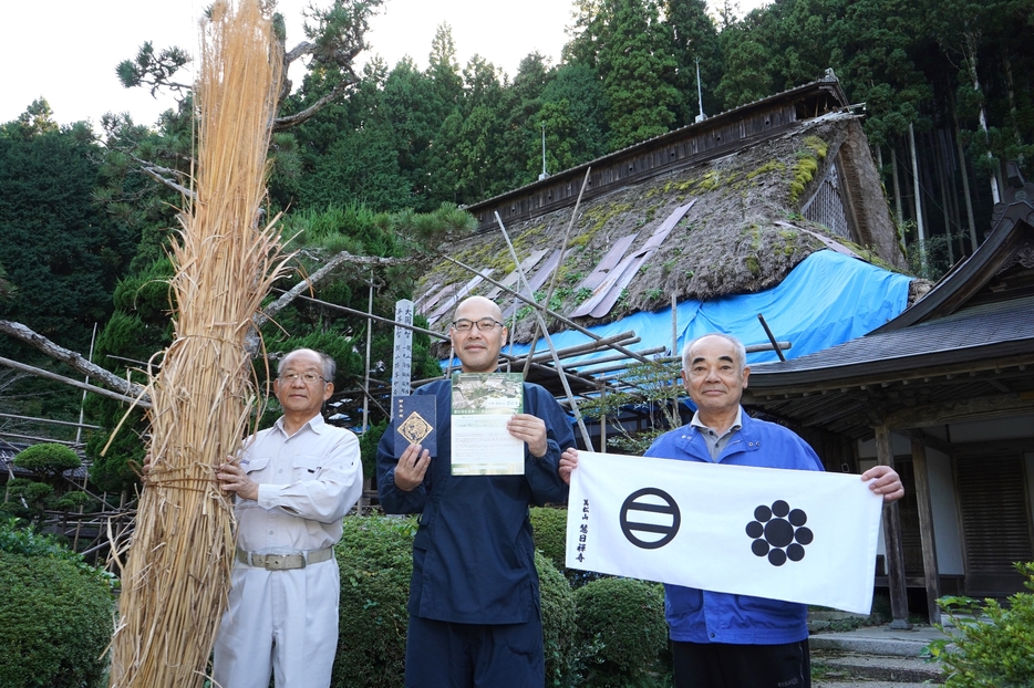 返礼品のオリジナルタオルや御朱印帳を手に、寄付の協力を呼びかける門脇住職（中央）と総代ら＝兵庫県丹波市山南町太田で