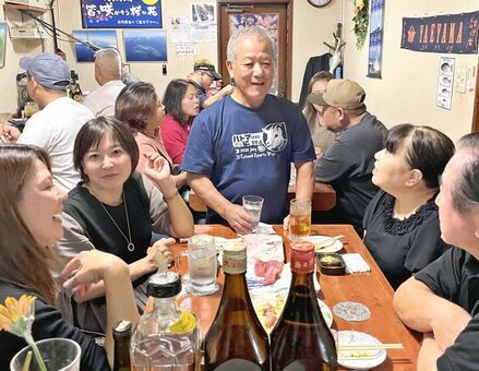 閉店を惜しむ客らとお酒を酌み交わす冨里勝行さん（中央）＝１０月１９日、那覇市大道