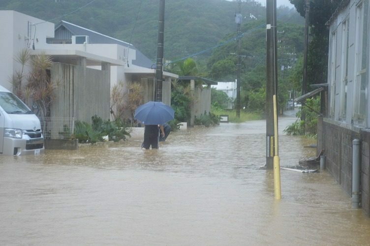 冠水した道路を歩く住民＝10日午前10時半ごろ、名護市稲嶺