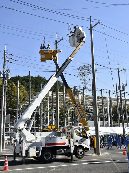 全国の一般送配電事業者の作業訓練で、切れた電線を仮復旧する作業員＝20日午前、広島市