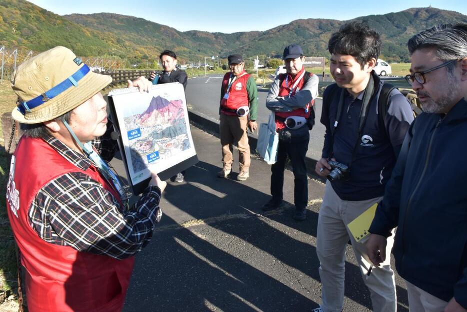 筑波山地域ジオパークの現地調査でガイドの説明を聞く調査員2人(右)=つくば市北条