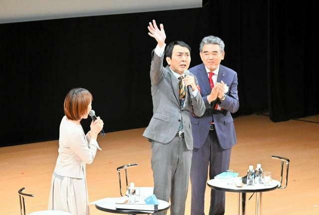 会場に手を振るアンガールズの田中卓志さん。右は越智光夫学長=2024年11月2日午後4時0分、広島県東広島市、副島英樹撮影