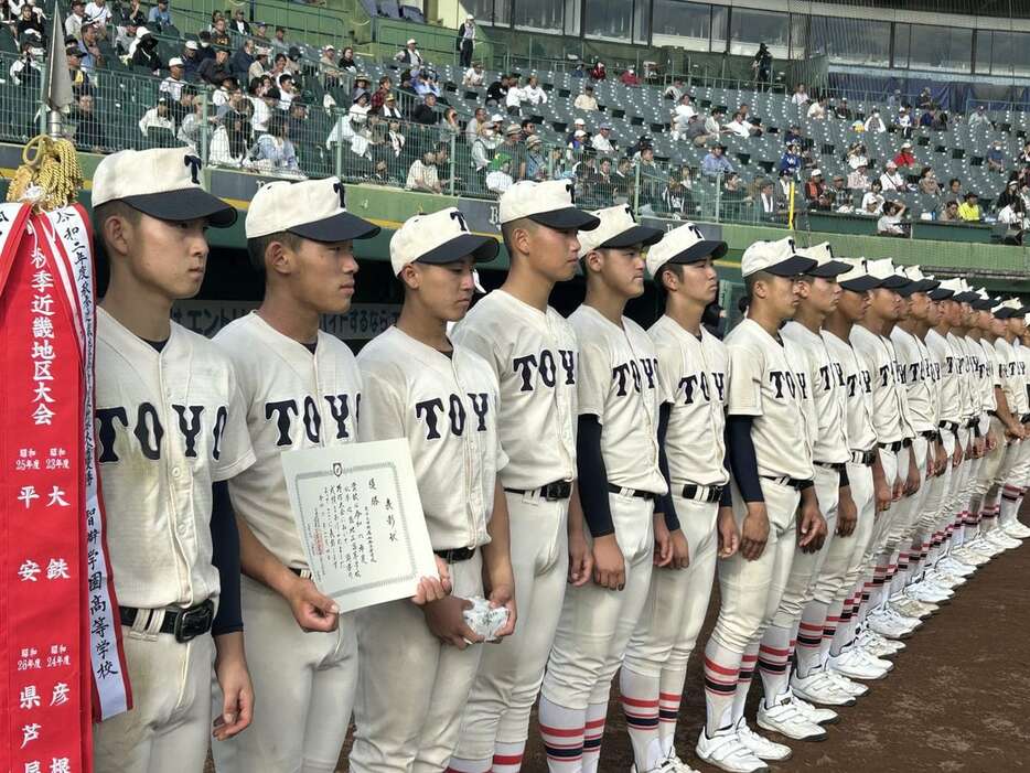 優勝旗を受け取り、ベンチ前で整列する渡辺拓主将（左端）ら東洋大姫路ナイン＝４日、ほっともっと