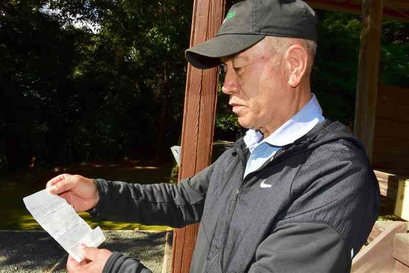 さい銭箱に入っていた謝罪の手紙を見つめる戸島神社総代会の桂良三さん＝6日、熊本市東区