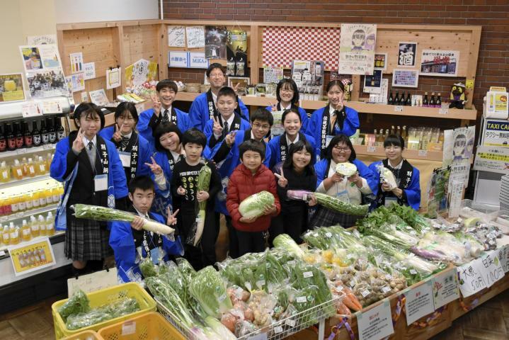 丹精の野菜を手に笑顔を見せる中学生ら