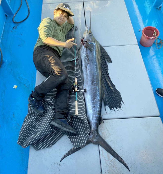 約２メートルのさおで釣り上げたバショウカジキと並ぶ川口龍之介さん（提供写真）