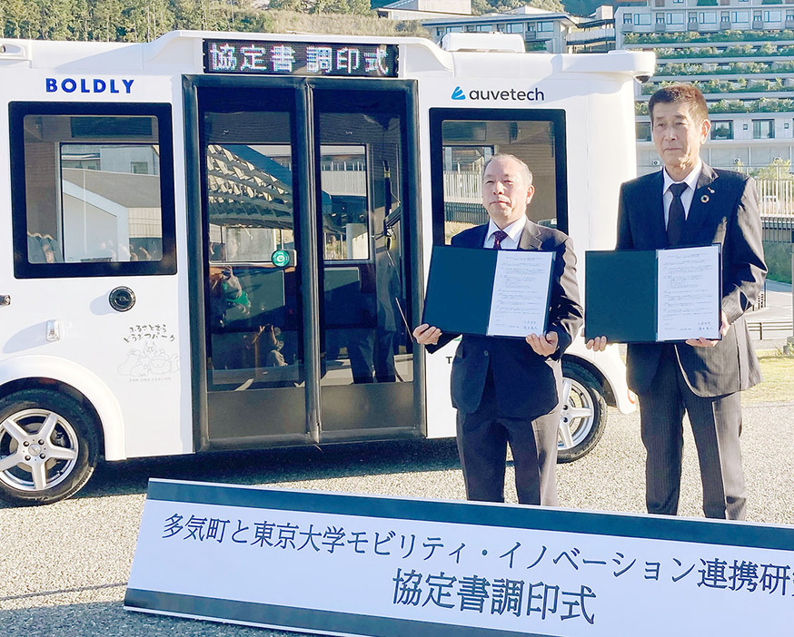 自動運転車両の前で、「レベル4」の運行に向けて協定を結んだ久保町長（右）と須田機構長＝多気町ヴィソンで（町提供）