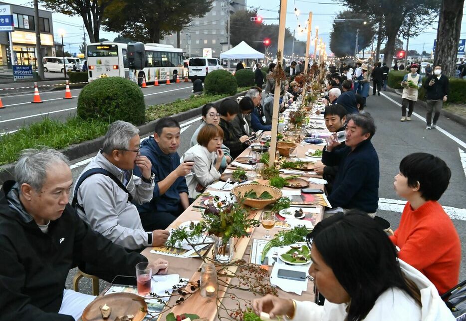 ロングテーブルで食事を楽しむ来場者ら