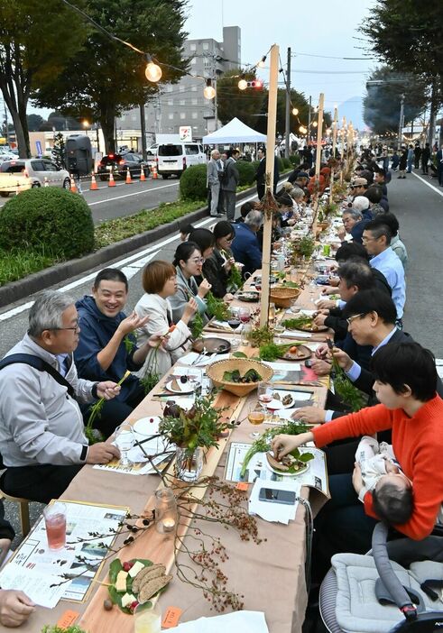 ロングテーブルで食事を楽しむ来場者ら